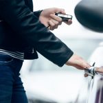 Beautiful young woman opening her car.